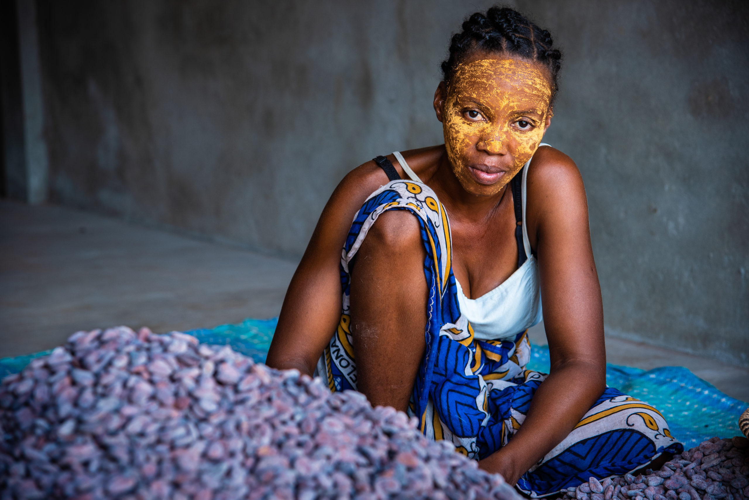 female Malagasy cocoa farmer with face paint sorting cocoa beans. Photo credit Beyond Good by Madecasse